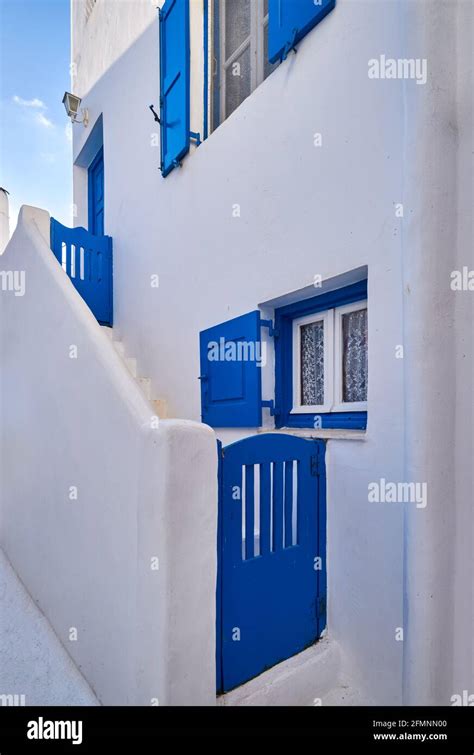 Une maison traditionnelle des Cyclades avec ses murs blancs, ses volets bleus et un bougainvillier en fleurs