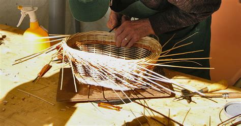 Gros plan sur les mains d'un vannier tressant de l'osier
