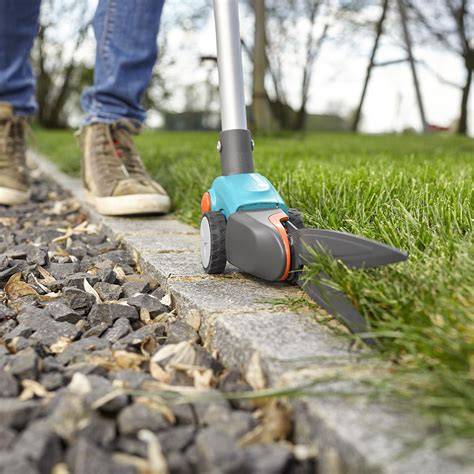 Un jardinier utilisant une cisaille à gazon pour tailler les bordures d'une allée