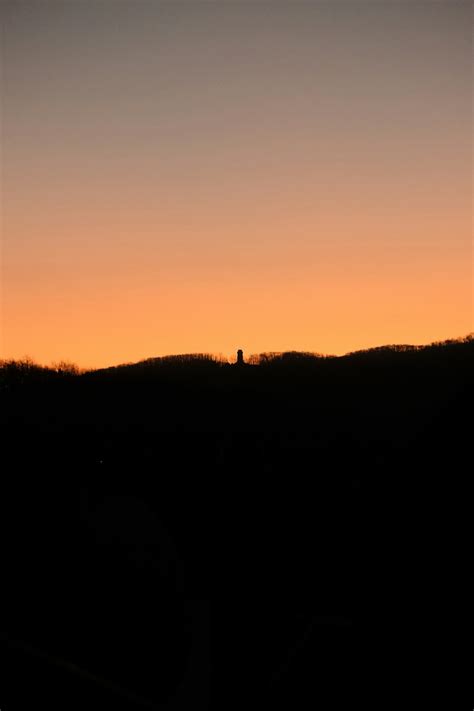 Silhouette d'une personne nue sur une colline au coucher du soleil