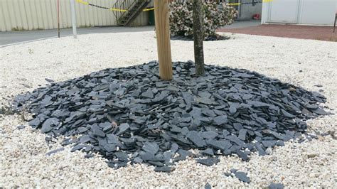 Paillettes d'ardoise grises et noires disposées dans un jardin