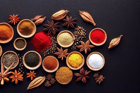 Assortiment d'épices dans des coupelles : curry, muscade, curcuma et graines de courge