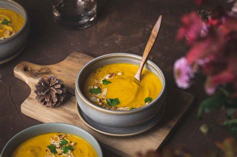 Velouté de potimarron servi dans une coque de courge évidée, agrémenté de graines grillées