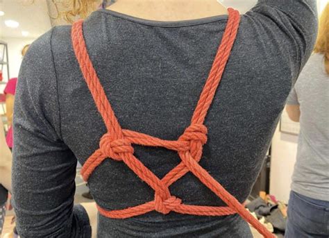 Gros plan sur des mains attachant des cordes de shibari autour d'un corps