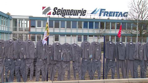 Blouses de travail accrochées aux grilles d'une usine