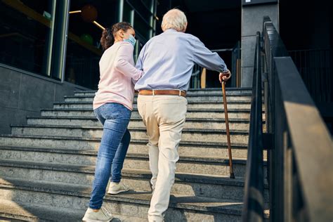 Personne âgée montant les escaliers avec difficulté