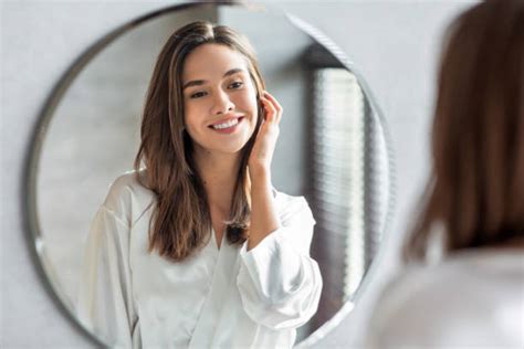 Femme souriante se regardant dans un miroir, portant de la lingerie