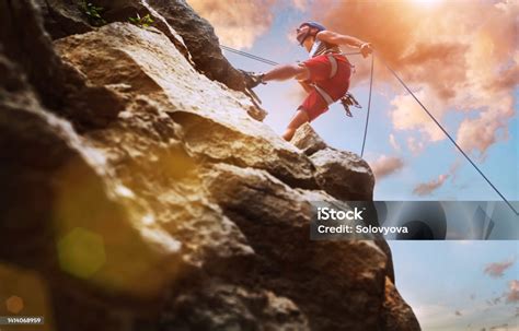 Grimpeur sur une falaise rocheuse au coucher du soleil