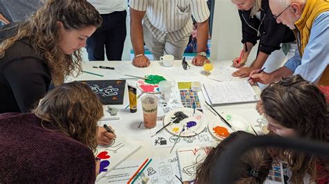 un groupe de personnes souriantes réalisant des couronnes de fleurs lors d'un atelier créatif