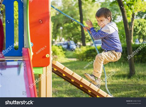 Un enfant escaladant un filet à grimper sur une aire de jeux