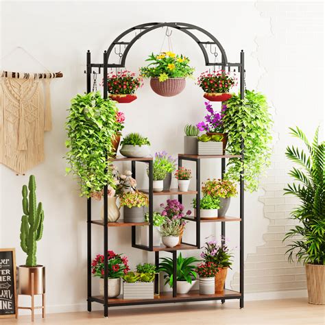 une étagère de jardin en fer forgé élégante remplie de plantes en fleurs sur une terrasse en bois