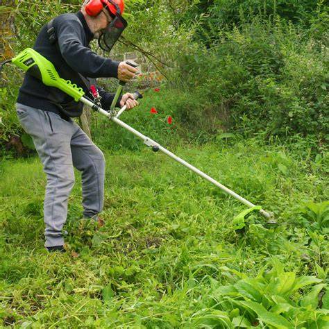 Débroussailleuse électrique en action, coupant l'herbe le long d'une bordure