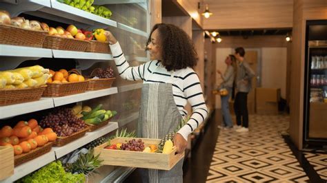 Employé de supermarché réapprovisionnant le rayon fruits et légumes