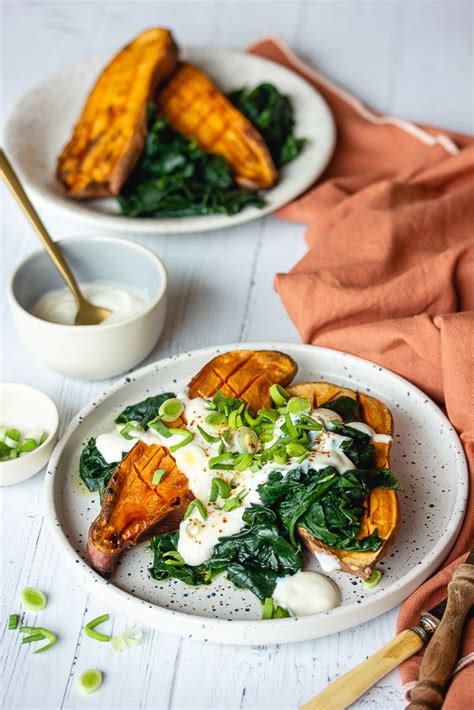 Patate douce rôtie coupée en deux et garnie d'épinards et d'une sauce blanche