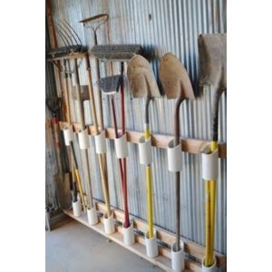 Outils à manche rangés dans des tubes PVC fixés au mur