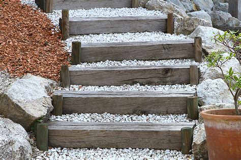 Escalier en traverses de bois brut intégré dans un chemin de gravier