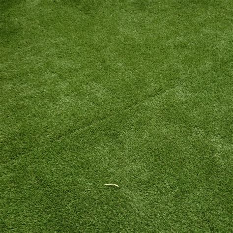 Gros plan sur les brins de gazon synthétique de différentes longueurs et teintes