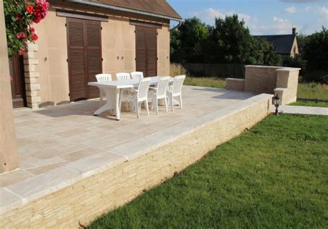 Un jardin aménagé avec des murets en pierre et une terrasse
