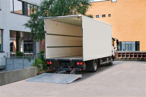 Schéma illustrant le transport sécurisé d'un olivier sur palette par camion avec hayon