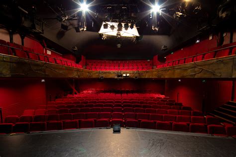 Une scène de théâtre contemporain avec des projecteurs et un public attentif