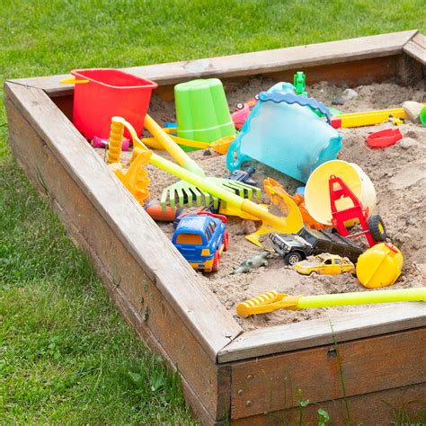 Aire de jeux sécurisée pour enfants avec bac à sable et balançoire dans un jardin verdoyant