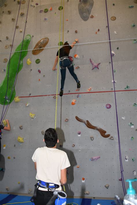 Un moniteur d'escalade accompagnant un grimpeur en situation de handicap dans une salle spécialisée