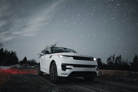 une voiture sur une route de nuit, bordée d'arbres et de fleurs lumineuses
