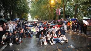 Spectateurs à Roland-Garros sous la pluie avec parapluies et ponchos
