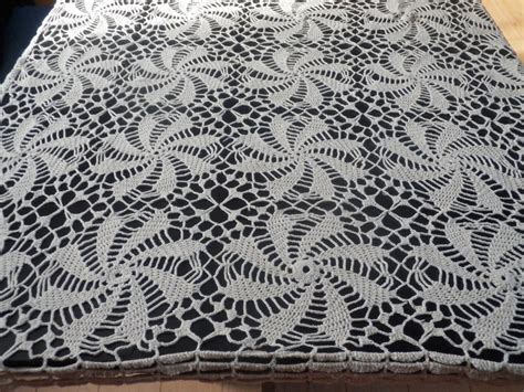 Détail rapproché d'une bordure en crochet travaillée avec une texture en relief, posée sur un tissu en lin naturel