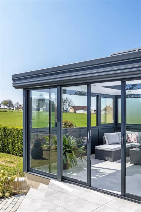 Véranda moderne avec baies vitrées donnant directement sur un jardin verdoyant