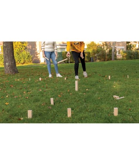 un plateau de jeu en bois type Kubb posé sur une pelouse coupée ras