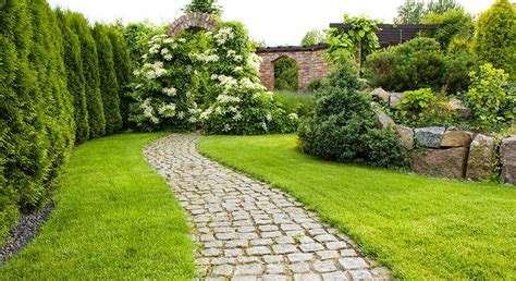 Jardin paysager avec allée bordée de fleurs et d'arbustes variés