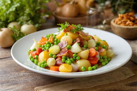 Table dressée avec une jardinière de légumes accompagnée d'une tranche de rôti et d'un verre de vin
