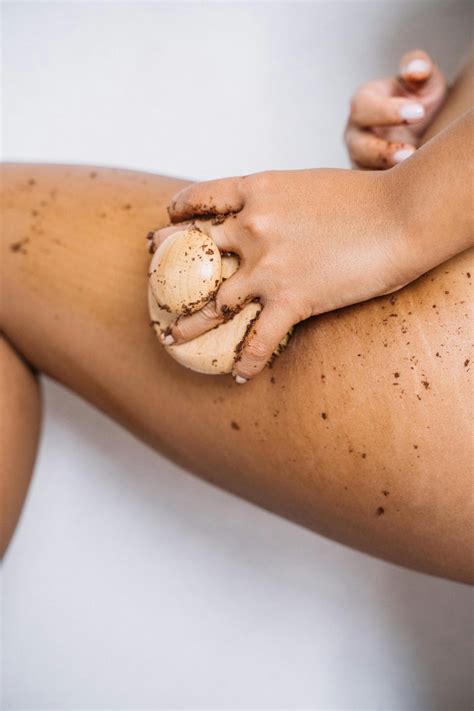 Femme appliquant un soin au marc de café sur le corps sous la douche
