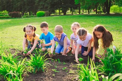 Photo d'enfants de maternelle plantant dans des demi-bouteilles en plastique décorées