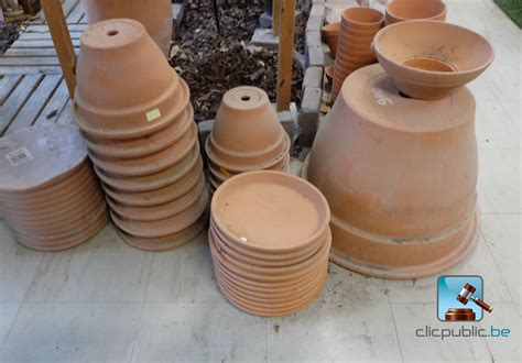 Exposition de différents modèles de pots en terre cuite et plastique sur une terrasse