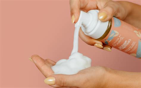 Main appliquant de la mousse sur des cheveux bouclés et humides