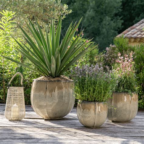Une collection variée de pots et jardinières en terre cuite disposés sur une terrasse ensoleillée