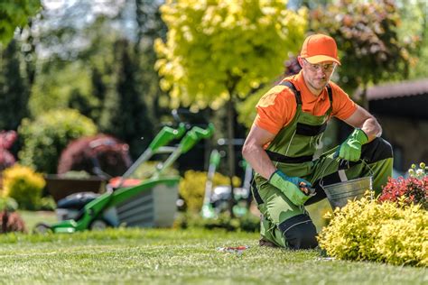 Un jardinier professionnel en train de débroussailler un terrain en pente avec un équipement de sécurité complet