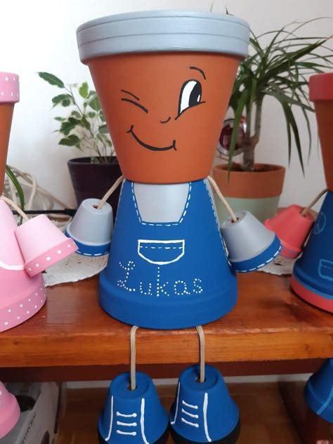Enfant décorant un pot de fleurs en terre cuite avec de la peinture et des pinceaux