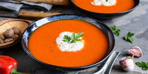 Bol de soupe veloutée de poivrons rouges fumants avec une touche de crème et de basilic frais
