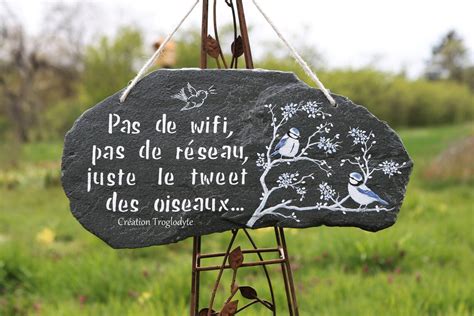 Un jardin paisible avec une ardoise artisanale portant une citation inspirante posée sur un massif de fleurs