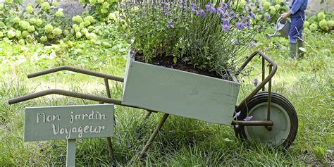 Une brouette ancienne transformée en jardinière fleurie et potagère dans un jardin ensoleillé