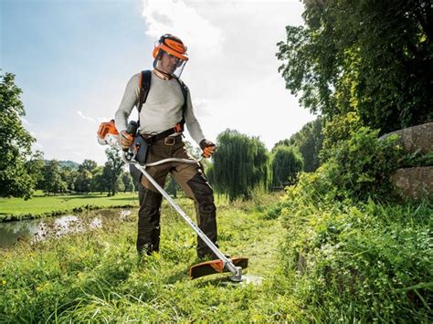 Tondeuse débroussailleuse thermique en action dans un champ d'herbes hautes