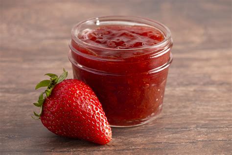 des bocaux de confiture de fraises faits maison sur une table en bois