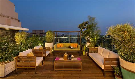 Exemple d'aménagement de toit-terrasse avec mobilier en bois, brise-vue végétalisé et éclairage d'ambiance