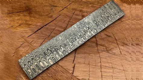 Vue rapprochée sur la texture d'une lame en acier damas poli miroir