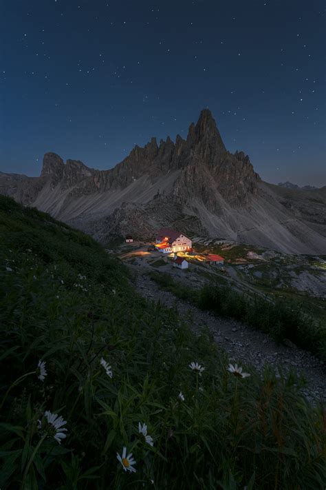 Photographie d'un refuge de haute montagne sous un ciel étoilé