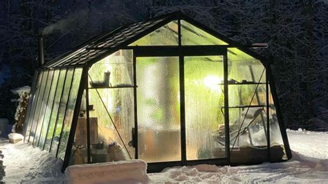une serre de jardin en hiver sous la neige avec des semis à l'intérieur