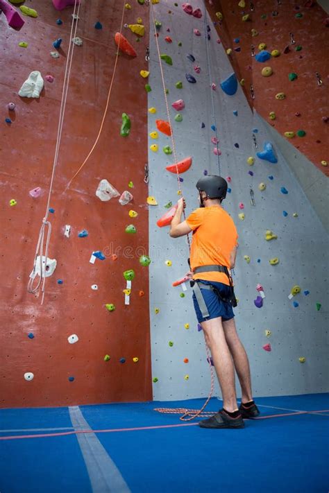 Un grimpeur concentré seul face à un mur d'escalade en salle